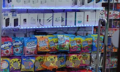 A row of 'snus' nicotine pouches and vapes are sold above bags of sweets and popular Prime drinks on Oxford Street