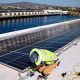 A worker installs solar panels on a 4-acre solar rooftop at AltaSea's research and development facility at the Port of Los Angeles in Los Angeles, California