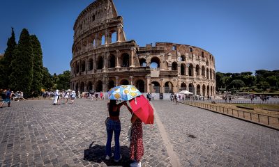 Tourists hold umbrellas to protect themselves from the sun near the Colosseum during a long heat wave with temperatures reaching 113°F and feeling hotter in Rome, Italy