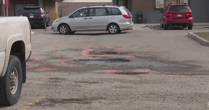 Southeast Calgary residents frustrated after strip mall parking lot potholes damage vehicles - Calgary